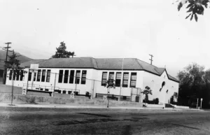 Side view of St. Dominic Catholic Church and school, located on the northeast corner of Maywood and Merton avenues in Eagle Rock. St. Dominic School was founded in 1925, four years after the parish was established. It was dedicated on February 24, 1925, and officially opened on September 8, 1925 with four teachers and approximately 100 students.